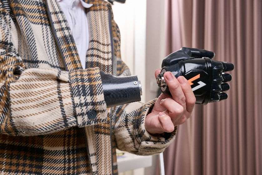 An upper limb young man wearing a cargo jacket is take out the Vulcan hand from his socket